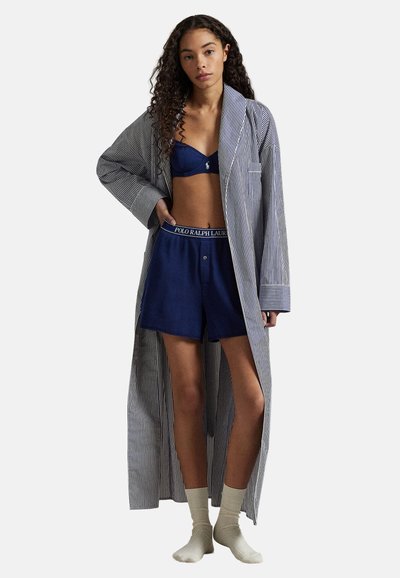 Μακρύ ριγωτό ρόμπα πάνω από σκούρο μπλε σουτιέν και σορτς που ταιριάζουν, με ζώνη Polo Ralph Lauren. Το μοντέλο φορά ανοιχτόχρωμες κάλτσες.