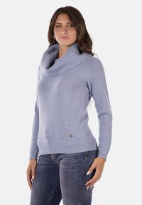 Maglione azzurro chiaro con collo a scialle, polsini e orlo a costine. Presenta un piccolo logo in accento sul lato. Realizzato in un tessuto a maglia testurizzato.