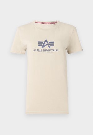 Beige puuvillapaita lyhyillä hihoilla, jossa on laivastonsininen painettu logo "Alpha Industries" ja punainen lappu kauluksessa.