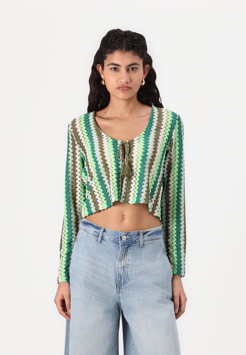 Horgolt cropped top, zigrábra mintázva zöld, fehér és barna színekben. Hosszú ujjak, elöl kötött részlettel és kerek nyakkivágással.