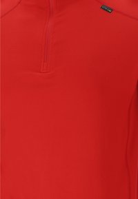Rød pullover med halv-zip krave, lavet af glat, letvægtsstof. Har flade sømme og et lille mærke på øverste venstre side.