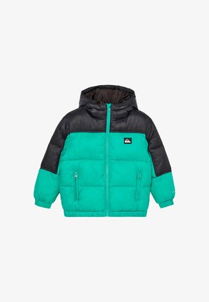 Kind trägt eine türkis-schwarze Daunenjacke, schwarze Mütze, rote reflektierende Sonnenbrille und dunkelblaue Hose und steht vor einem schlichten Hintergrund.