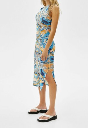 Robe ajustée colorée avec un motif tourbillonnant en bleu, orange et jaune, comportant une fente haute d'un côté et un tissu lisse et extensible.