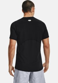 Camiseta deportiva negra con mangas cortas, escote redondo y costuras tonales sutiles. Incluye un pequeño logo en la parte posterior.