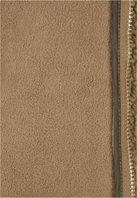 Bruine fleece stof met een zachte textuur, voorzien van een ritsdetail aan de rechterkant, omlijst door een gladde beige voering.