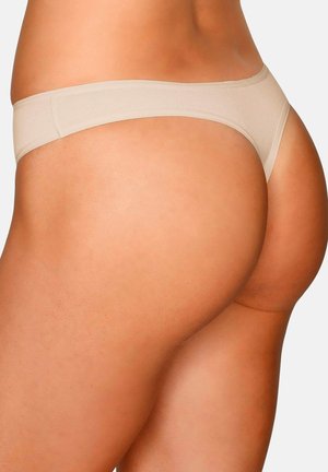 Beige nahtloser Tanga, getragen an den Hüften und am Gesäß einer Frau, von hinten vor einfachem Hintergrund gezeigt.