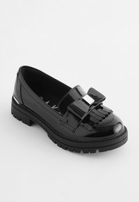 Svart lackläder loafer med en rosettdetalj, fransade accenter och en tjock gummisula. Designen har en glänsande yta och kontrasterande beslag.