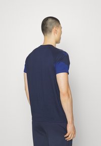 Marinblå tränings-t-shirt med korta ärmar, med en kontrasterande blå axelpanel och en mjuk yta. Enkel, klassisk passform.