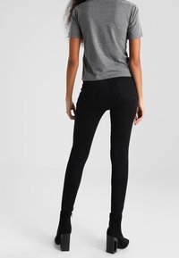 Czarne wąskie dżinsy zestawione z szarym t-shirtem z krótkim rękawem, o dopasowanym kroju i gładkiej fakturze, noszone z botkami na obcasie.