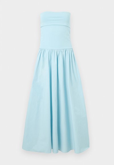 Φόρεμα μάξι ανοιχτό μπλε χωρίς τιράντες, με σφηκοφωλιά στη μέση και ολόκληρη, ρέουσα φούστα σε ουδέτερο φόντο.