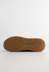 Suola in gomma marrone con un motivo texturizzato, caratterizzato da dettagli a zigzag e circolari. Logo del marchio ben visibile sul lato.