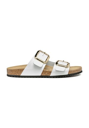 Sandales blanches à deux sangles avec boucles en ton doré, semelle en liège et semelle extérieure noire texturée. Design plat avec sangles réglables.