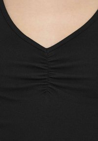 Top nero a coste con scollatura a V e dettaglio arricciato al centro. La texture del tessuto è leggermente rigata e aderente.