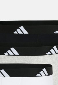 Boxer aderenti da uomo in bianco e nero con fasce elastiche a contrasto che mostrano il logo Adidas. Comprende tre paia in colori variabili: nero, grigio e bianco.