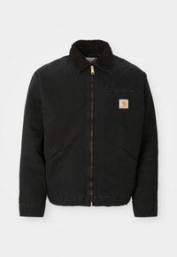 Schwarze zip-up Jacke mit braunem Cordkragen, zwei Seitentaschen und einem kleinen quadratischen Carhartt-Logo-Patch auf der linken Brust.