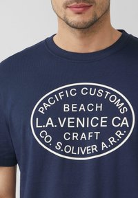 Marineblauwe t-shirt van katoen, met een grote witte ovale grafiek voorzien van de tekst: "PACIFIC CUSTOMS BEACH L.A.VENICE CA CRAFT CO. S.OLIVER A.R.R."