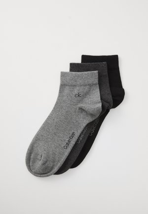 Juego de calcetines de algodón en gris, gris oscuro y negro. Cada par cuenta con un puño acanalado y el logo "ck" en negro en el lateral.