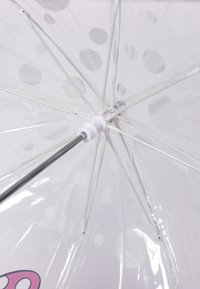 Transparante paraplu met grote witte stippen, plastic canopy, metalen frame en een wit plastic handvat en gewrichten. Eenvoudig en functioneel ontwerp.