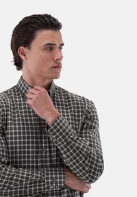 Grün-graue karierte Knopfhemd mit einem strukturierten Kragen, langen Ärmeln und Manschettenknöpfen, die eine weiche Textur aufweisen.