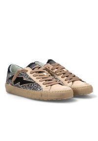 Zapatillas bajas en beige y negro con cordones en tono marrón, paneles laterales plateados brillantes y un diseño de rayo negro sobre un fondo blanco.