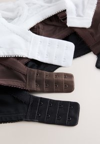 Drei BHs in Weiß, Braun und Schwarz flach liegend, mit Haken- und Ösenverschluss und drei Reihen für verstellbare Passform.