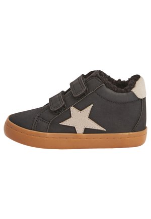 Black toddler shoe with tan rubber sole, two Velcro straps, beige star patch, and fuzzy interior lining.