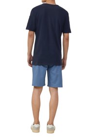 Marineblauwe katoen T-shirt met korte mouwen, gecombineerd met lichtblauwe shorts en witte sneakers. Het shirt heeft een ronde hals en een ontspannen pasvorm.