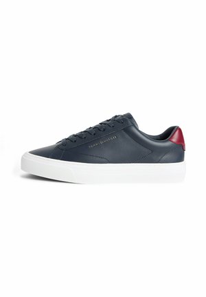Laag uitgesneden sneaker in marineblauw met witte zool, rood hieldetail, veters en subtiel goudkleurig "Tommy Hilfiger"-logo op de zijkant.