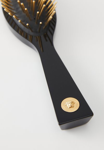 Μαύρη βούρτσα μαλλιών με χρυσά καρφιά, με φαρδιά λαβή. Εντυπωσιακό χρυσό έμβλημα στη βάση, σχεδιασμένη για αποτελεσματικό χτένισμα.