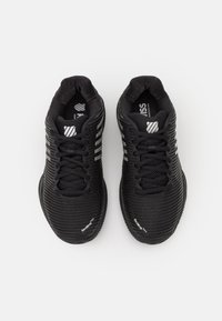 Černé sportovní boty s texturovaným síťovinovým svrškem, kulatou špičkou, šněrovacím designem a kontrastními bílými akcenty na stranách a logu.