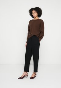 Brauner Strickpullover, schwarze maßgeschneiderte Hose und burgunderrote High-Heels. Das Outfit zeichnet sich durch eine lässige Passform und ein schlichtes Design aus.
