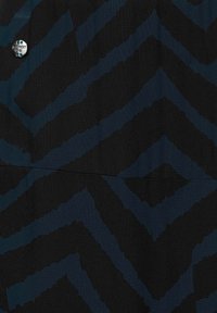 Černá látka se zigzagovým vzorem v tmavě modrých odstínech. Má kovový knoflík s logem „Street One“. Hladký povrch.