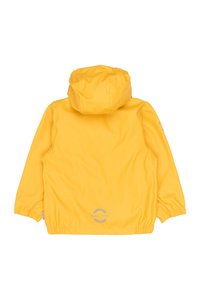 Chaqueta impermeable amarilla con capucha, puños elásticos y textura suave. Presenta un logo circular en la parte baja de la espalda. Diseño sencillo.