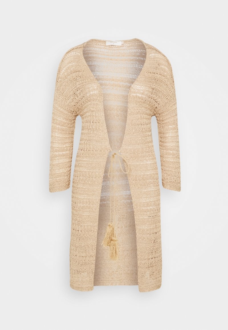 Beige, open-knit cardigan with a deep V-neck, 3/4 sleeves, and a drawstring closure featuring a tassel detail at the waist.