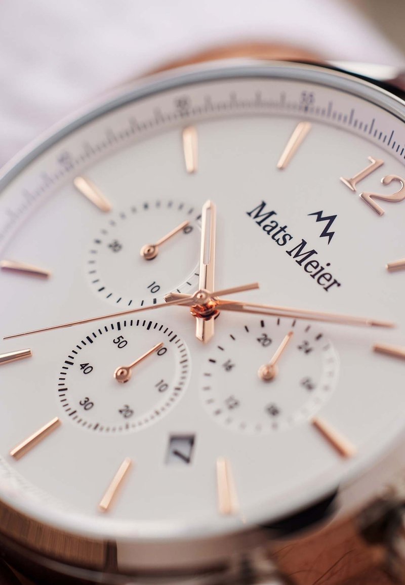 Rose gold chronograph watch with a white dial, three sub-dials, rose gold hour markers, and a date window at the 6 o'clock position.