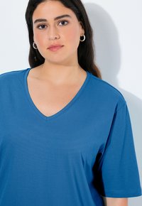 Blue, short-sleeved t-shirt in smooth fabric with a v-neck design. The shirt features a relaxed fit and subtle stitching details.