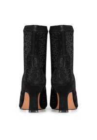 Botines de ante negros con una superficie texturizada adornada con pequeños tachuelas metálicas incrustadas y un tacón cuadrado. Aperturas estrechas en la parte superior.
