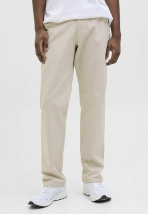 Beige, rechte pijpen van lichtgewicht stof, met een zachte textuur en subtiele zijzak, gecombineerd met witte sneakers.
