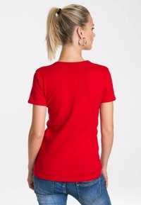 Red short-sleeve t-shirt made of cotton, featuring a round neckline and smooth texture, paired with blue denim jeans.
