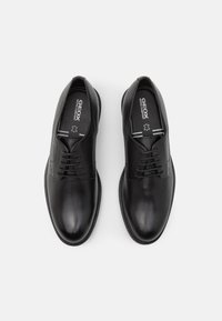 Chaussures de ville en cuir noir avec une finition lisse, dotées d'un design classique à lacets, d'une semelle en caoutchouc et de semelles intérieures avec logo.