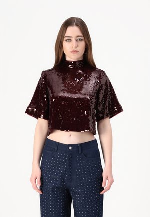 Burgunder sequins cropped topp med korte ermer og høy hals, kombinert med mørkeblå bukser med dekorative nagler.