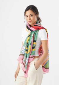Écharpe en soie colorée présentant des motifs de feuilles, de fleurs et de formes abstraites. Bords en rose avec des accents noirs et jaunes, texture légère.