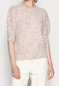 Jasno-beżowy sweter dzianinowy z krótkimi, bufkami i teksturowanym materiałem. Posiada okrągły dekolt i ściągacz na dolnej krawędzi.