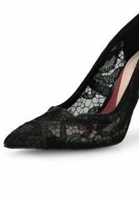 Chaussure à talon haut noire à bout pointu avec superposition de dentelle complexe et doublure intérieure beige et rouge sur fond blanc.