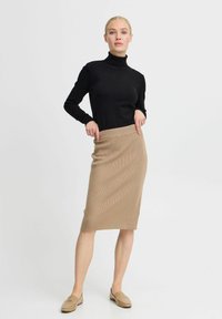 Un haut à col roulé noir associé à une jupe midi beige à côtes. La tenue présente une silhouette ajustée et des textures lisses et unies.