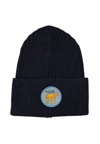 Marinblå ribbad strumpmössa med en rund tygmärke som har en tecknad ko-illustration. Märket har ljusblå kanter och text på svenska.