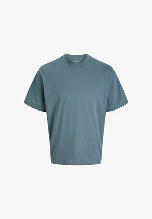 Szara koszulka z krótkim rękawem, połączona z czarnymi spodniami cargo z dużymi bocznymi kieszeniami oraz białymi sneakersami. Prosty, casualowy design.