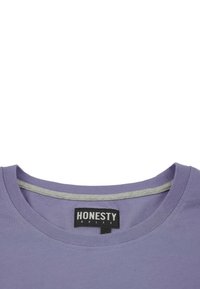 Lilla bomulds T-shirt med rund hals og grå indvendig trim. Har et sort mærke med teksten "ÆRLIGHED ER REGELEN." Glat tekstur.