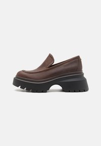 Scarpe in pelle marrone, slip-on, con una suola platform nera spessa e tagli curvi. Presentano una finitura liscia e dettagli di cucitura sottili.