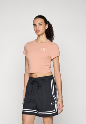 Light pink cropped t-shirt with a rounded neckline and short sleeves, paired with black athletic shorts featuring white side stripes and logo.
